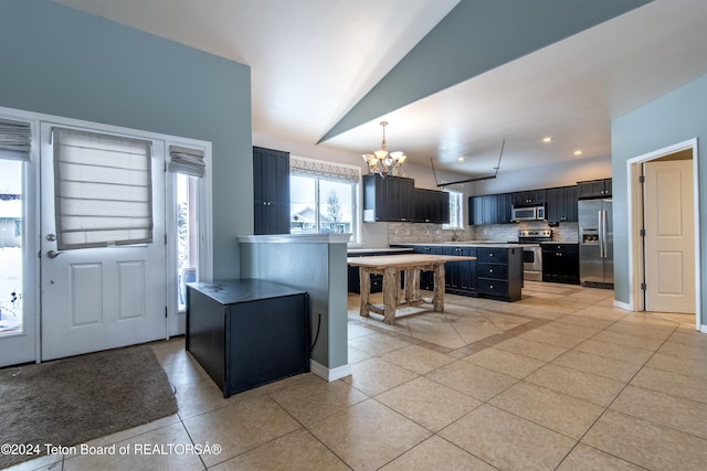 kitchen featuring lofted ceiling, decorative backsplash, a kitchen island, stainless steel appliances, and a chandelier