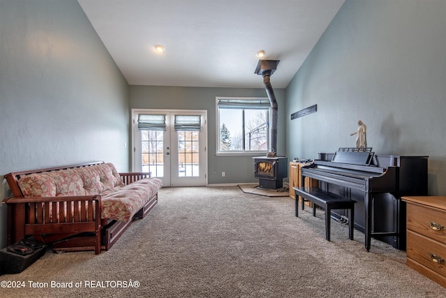 sitting room featuring carpet flooring, french doors, a wood stove, and lofted ceiling