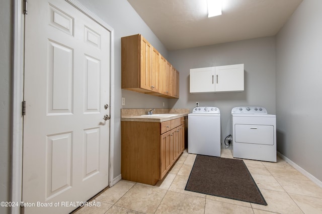 washroom featuring washing machine and dryer, sink, light tile patterned floors, and cabinets