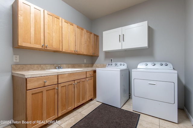 laundry area with washing machine and clothes dryer, sink, light tile patterned flooring, and cabinets