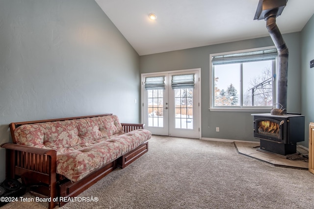 carpeted living room with french doors, vaulted ceiling, and a wood stove