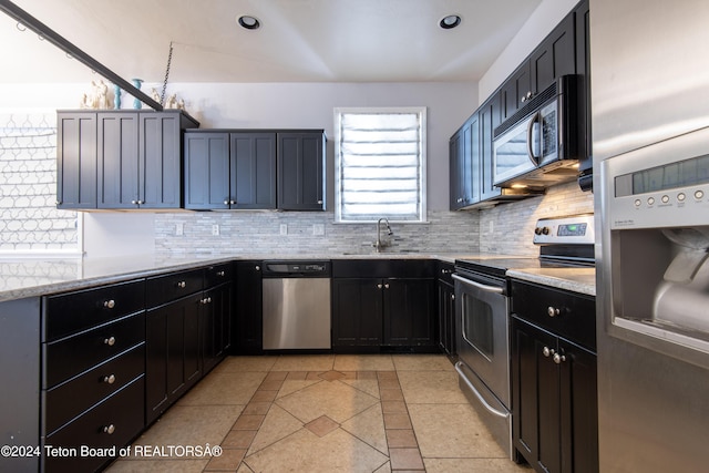 kitchen featuring light tile patterned flooring, appliances with stainless steel finishes, light stone countertops, and sink