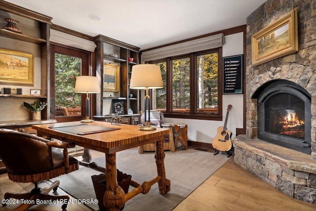 office area with a fireplace, ornamental molding, and light wood-type flooring