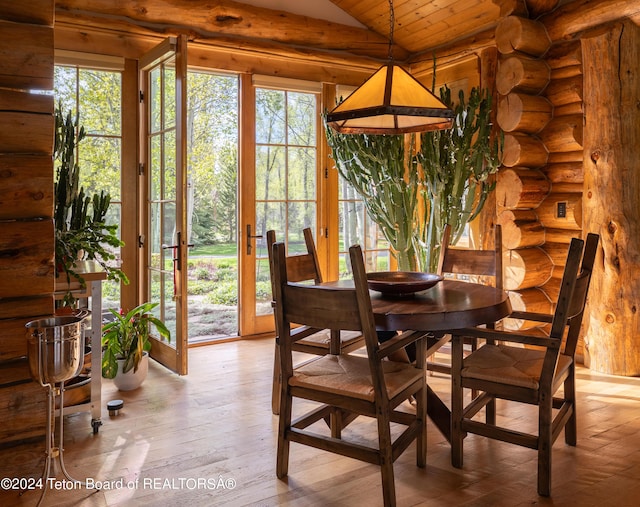 dining space featuring rustic walls, wood ceiling, light hardwood / wood-style flooring, and vaulted ceiling