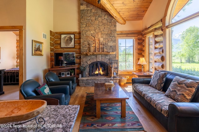 living room featuring a stone fireplace, plenty of natural light, wood ceiling, and wood-type flooring