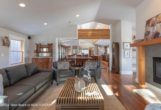 living room featuring wood-type flooring, vaulted ceiling, and a tiled fireplace