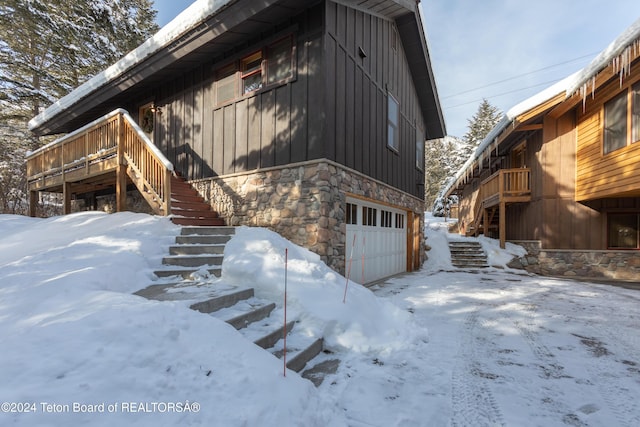 3470 W Mccollister Dr, Teton Village, WY 83025 - view of snow covered exterior featuring stairs, stone siding, a garage, board and batten siding, and a deck