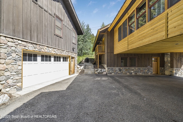 3470 W Mccollister Dr, Teton Village, WY 83025 - view of property exterior with stone siding, board and batten siding, driveway, and a garage