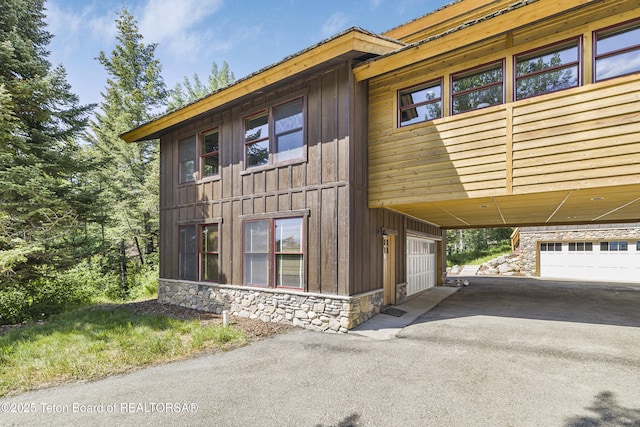 3470 W Mccollister Dr, Teton Village, WY 83025 - chalet / cabin featuring board and batten siding, stone siding, asphalt driveway, and a garage