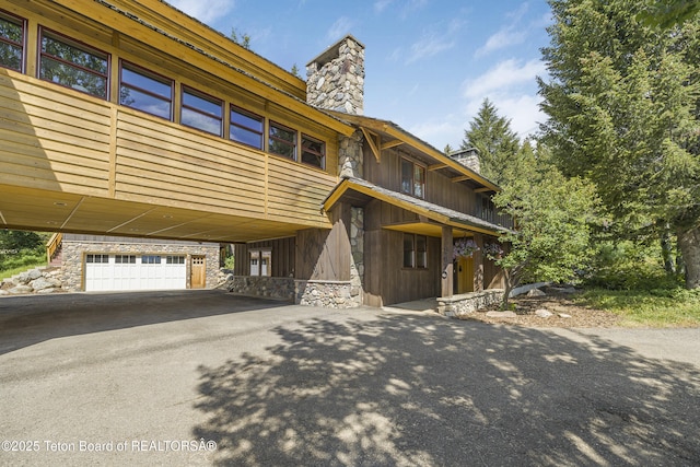 3470 W Mccollister Dr, Teton Village, WY 83025 - view of front of house featuring a chimney, asphalt driveway, and stone siding