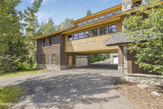 3470 W Mccollister Dr, Teton Village, WY 83025 - view of front facade featuring stone siding, asphalt driveway, a carport, and an attached garage