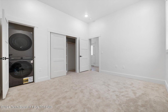 unfurnished bedroom with stacked washer / dryer and light carpet