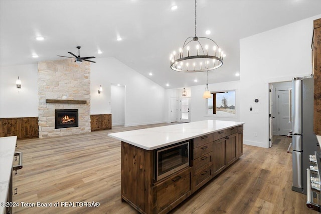 kitchen with decorative light fixtures, appliances with stainless steel finishes, light hardwood / wood-style flooring, and a kitchen island