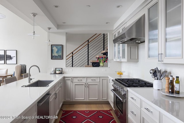 kitchen featuring pendant lighting, sink, wall chimney exhaust hood, appliances with stainless steel finishes, and kitchen peninsula