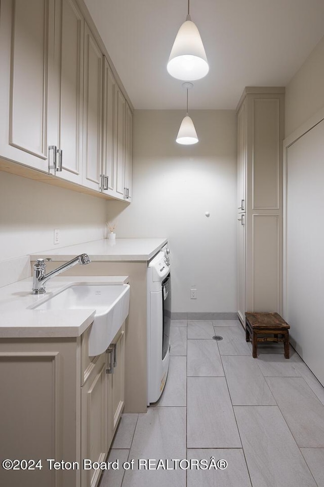 laundry area featuring cabinets, light tile patterned floors, sink, and washer / dryer