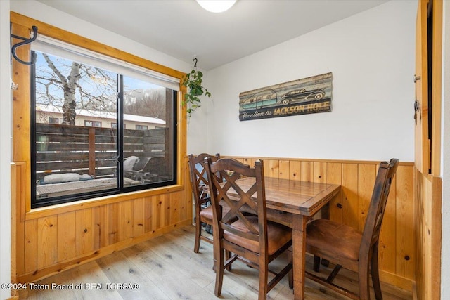 dining room featuring light wood-type flooring and wooden walls