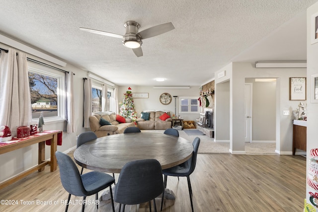 dining room featuring a textured ceiling, light hardwood / wood-style flooring, and ceiling fan