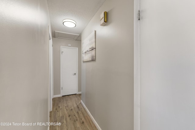 corridor with light hardwood / wood-style floors and a textured ceiling