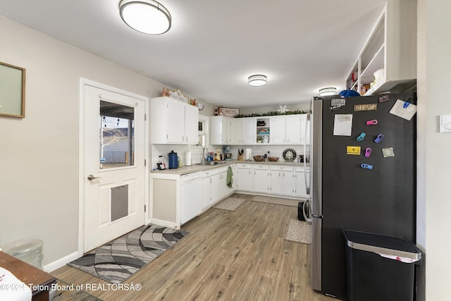 kitchen featuring stainless steel refrigerator, sink, white dishwasher, white cabinets, and light wood-type flooring