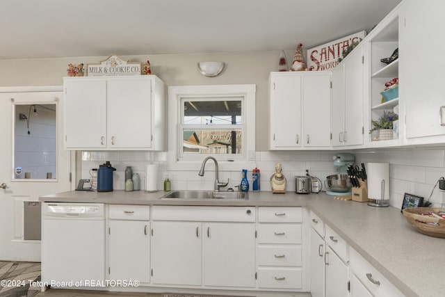 kitchen with backsplash, dishwasher, white cabinetry, and sink