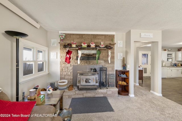 living room with carpet flooring, a wood stove, and a textured ceiling