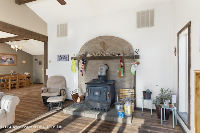 living room with hardwood / wood-style floors, vaulted ceiling with beams, a wood stove, and ceiling fan with notable chandelier