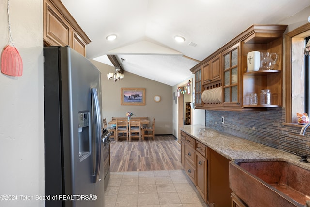 621 Mountain View Dr, Dubois, WY 82513 - kitchen with stainless steel refrigerator with ice dispenser, brown cabinets, lofted ceiling, tasteful backsplash, and light stone countertops