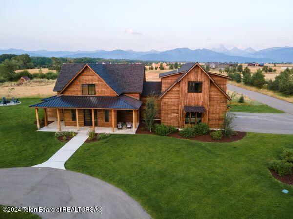 view of front of house with a mountain view, a porch, and a front yard