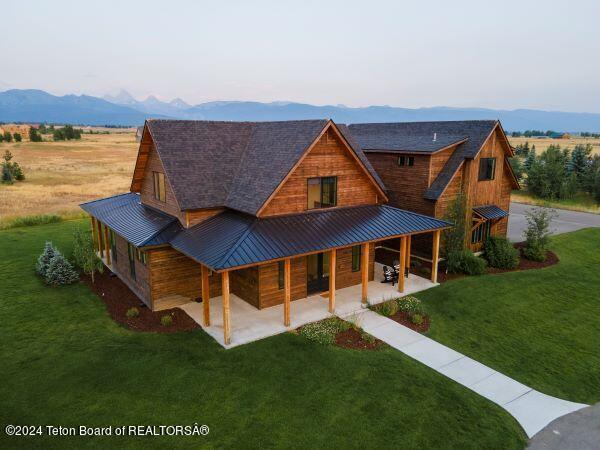 back of property featuring a mountain view and a yard