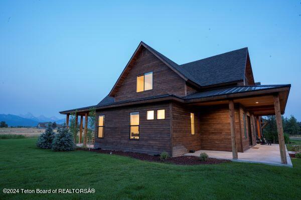 view of side of home featuring a mountain view, a yard, and a patio