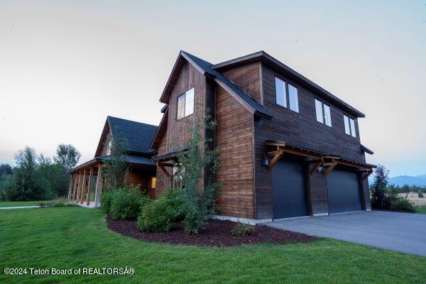 property exterior at dusk featuring a lawn and a garage