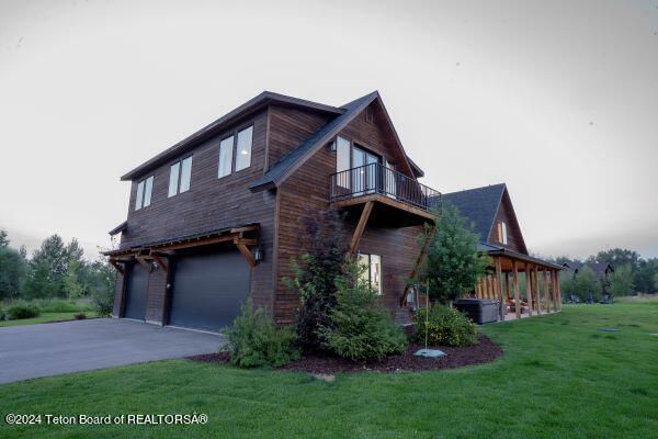 view of side of home featuring a garage, a balcony, and a yard