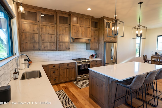 kitchen with sink, a center island, hanging light fixtures, a breakfast bar, and appliances with stainless steel finishes