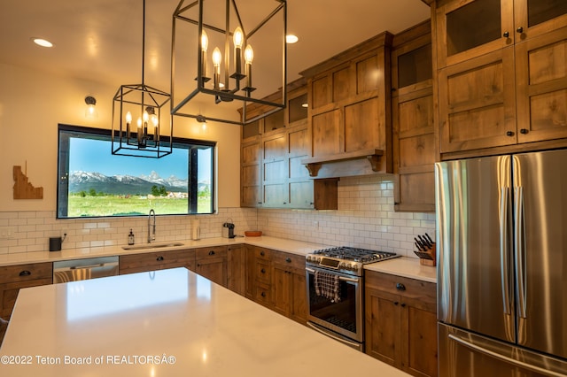 kitchen with decorative backsplash, appliances with stainless steel finishes, sink, an inviting chandelier, and hanging light fixtures