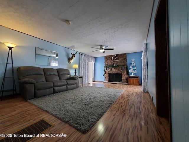 living room featuring a fireplace, hardwood / wood-style floors, and ceiling fan