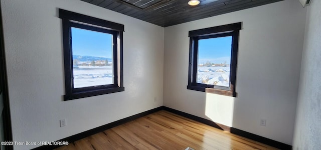 spare room with a mountain view, wood-type flooring, and wood ceiling