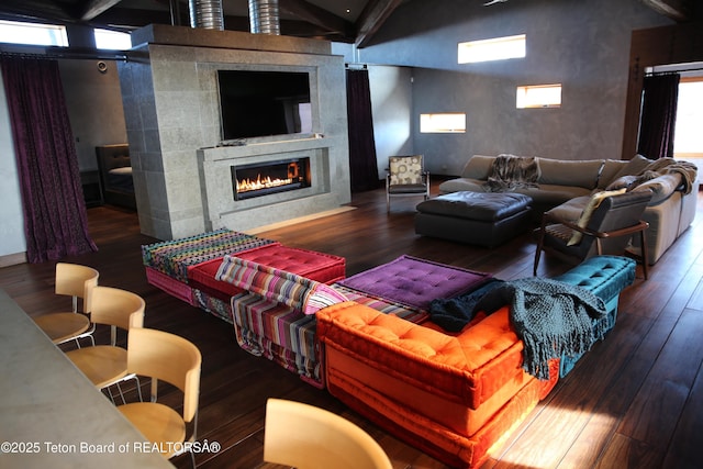 living room featuring a tile fireplace, beamed ceiling, and dark hardwood / wood-style floors