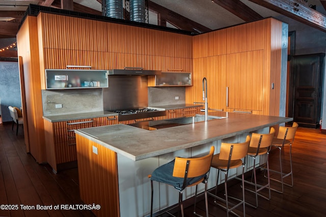 kitchen featuring dark wood-type flooring, lofted ceiling with beams, a spacious island, extractor fan, and black electric stovetop