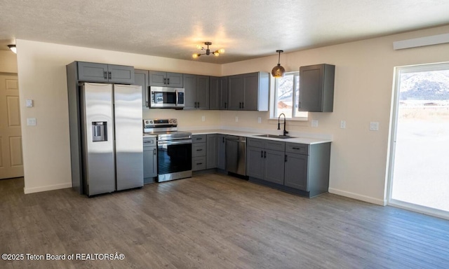 kitchen featuring dark wood finished floors, light countertops, gray cabinetry, appliances with stainless steel finishes, and a sink