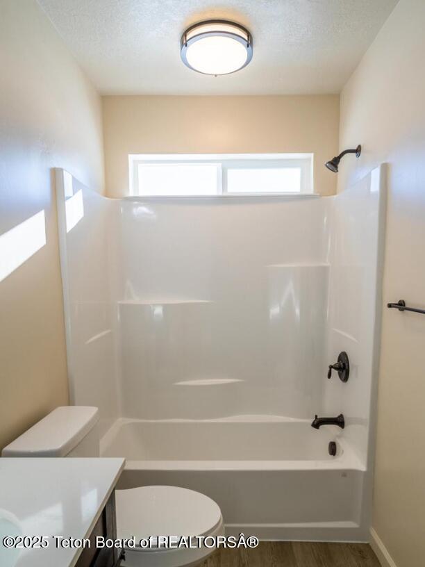 bathroom featuring bathing tub / shower combination, toilet, wood finished floors, a textured ceiling, and vanity