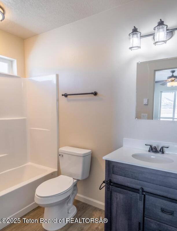 full bath featuring toilet, vanity, a textured ceiling, and wood finished floors