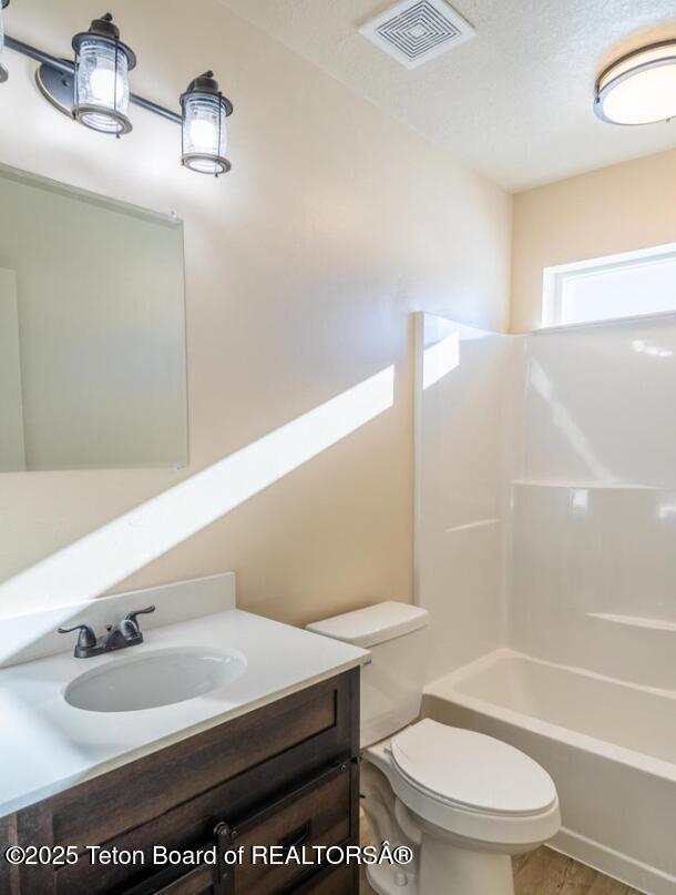 full bathroom with toilet, shower / tub combination, visible vents, and vanity