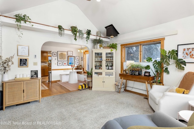 living room featuring an inviting chandelier, carpet, and high vaulted ceiling