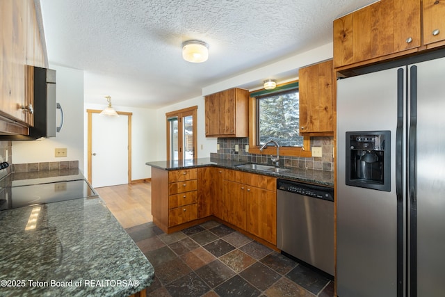 kitchen featuring sink, stainless steel appliances, kitchen peninsula, a textured ceiling, and decorative backsplash