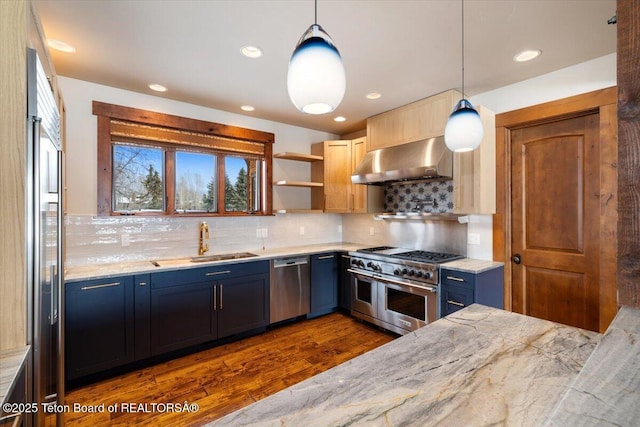 kitchen with exhaust hood, dark hardwood / wood-style floors, light stone countertops, appliances with stainless steel finishes, and decorative light fixtures