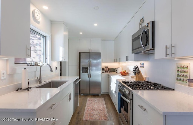 1875 W Cinnamon Teal Rd, Jackson, WY 83001 - kitchen with appliances with stainless steel finishes, a sink, light wood finished floors, recessed lighting, and white cabinets