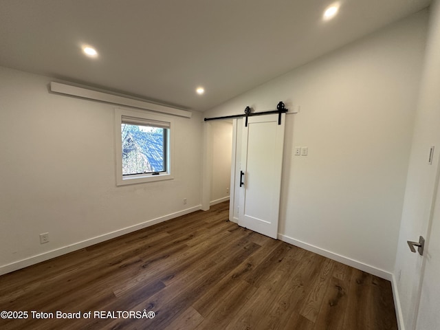 1875 W Cinnamon Teal Rd, Jackson, WY 83001 - unfurnished bedroom featuring a barn door, dark wood finished floors, recessed lighting, baseboards, and lofted ceiling