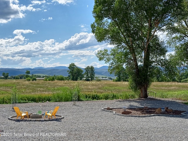 view of yard featuring a mountain view, a rural view, and an outdoor fire pit