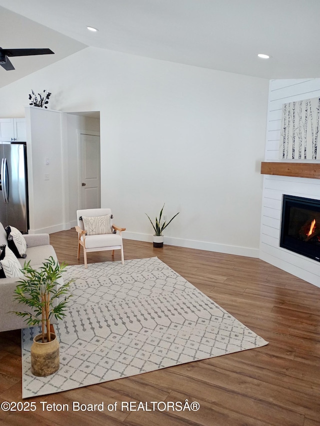 unfurnished living room featuring hardwood / wood-style floors, ceiling fan, a large fireplace, and vaulted ceiling