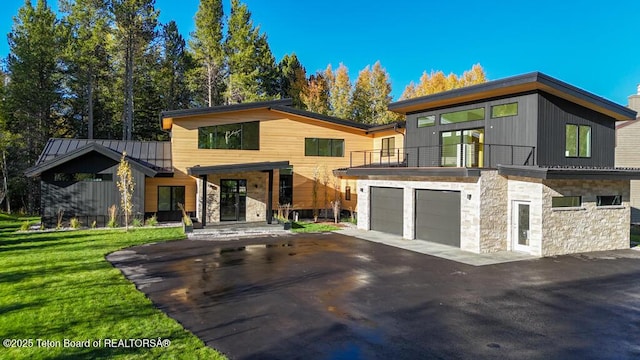 contemporary home featuring a balcony, a garage, and a front lawn